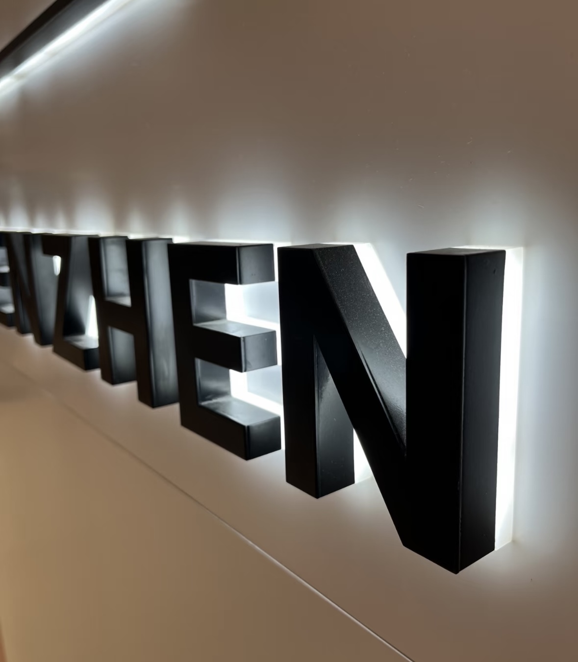 Real client installed shot of finished backlit halo‑illuminated metal signage on site